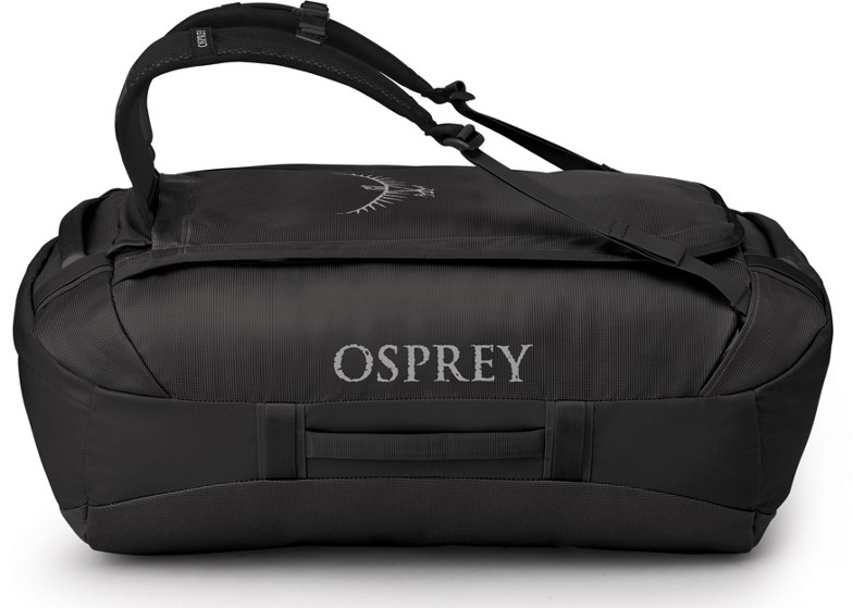 Osprey 65L transport duffel bag in use on a hiking trail, demonstrating its rugged design.