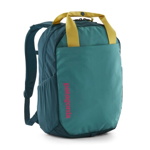 Patagonia Atom 20L tote pack in olive green, viewed from the front, showcasing its dual carry straps and compact design against a natural outdoor backdrop.
