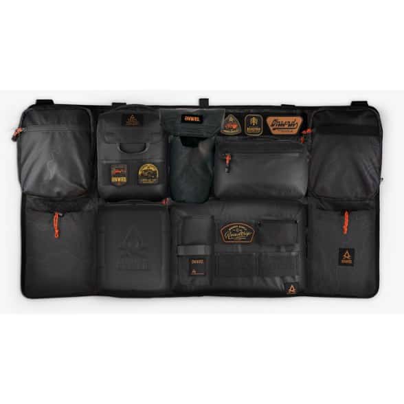A full view of the Onward Rover Bench Seat Organizer showcasing its various pockets and modular attachments, installed in the back of an SUV.