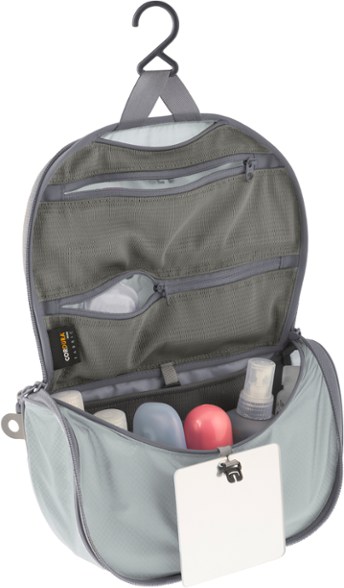 A neatly packed Voyager Pro hanging toiletry bag suspended open, showing multiple mesh pockets filled with travel-sized toiletries.